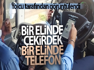 Şehirlerarası otobüs şoförünün bir elinde telefon, bir elinde çekirdek