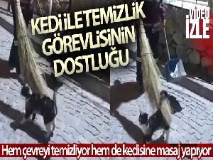 Hem çevreyi temizliyor hem de sokak kedisine süpürgesi ile masaj yapıyor