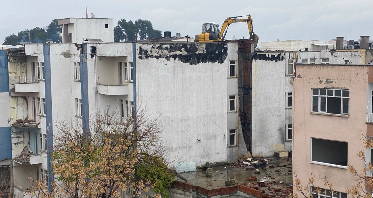 İş makinası yıkım için ağır hasarlı binanın üzerine çıkarıldı