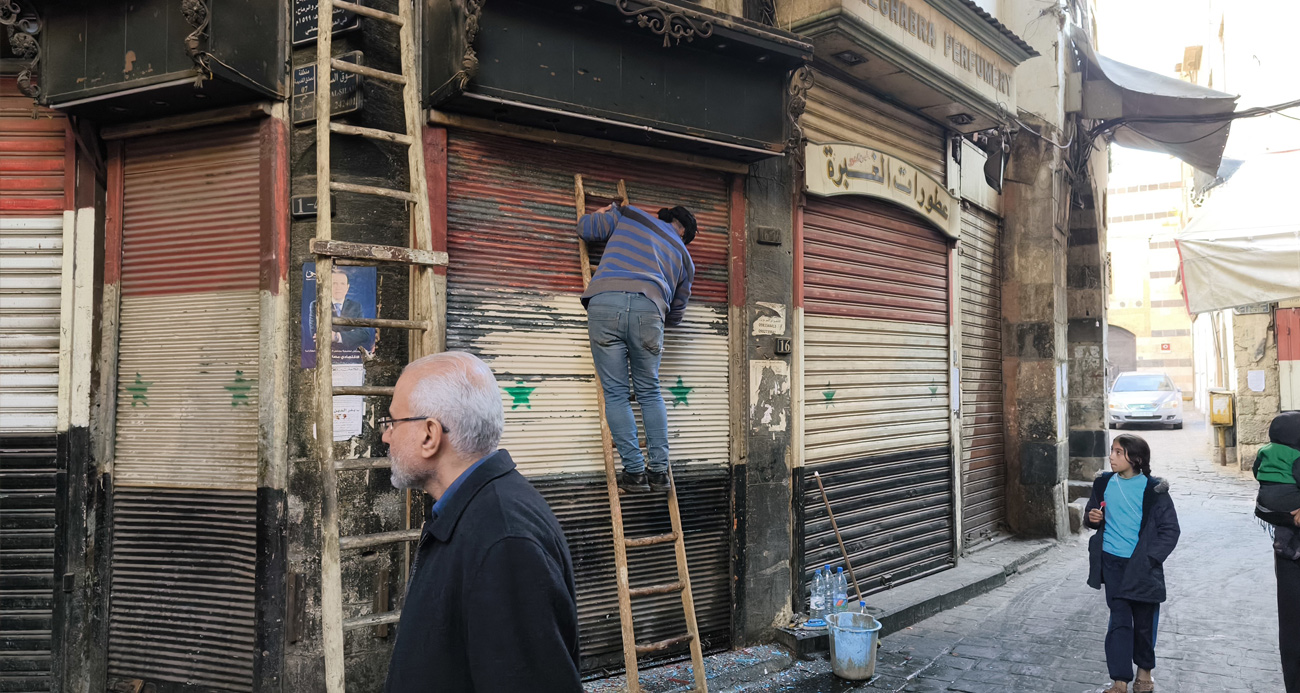 Esnaflar kepenklerindeki eski Suriye bayraklarını kazımaya başladı